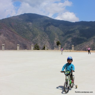 Little boy cycling around Buddha statue..